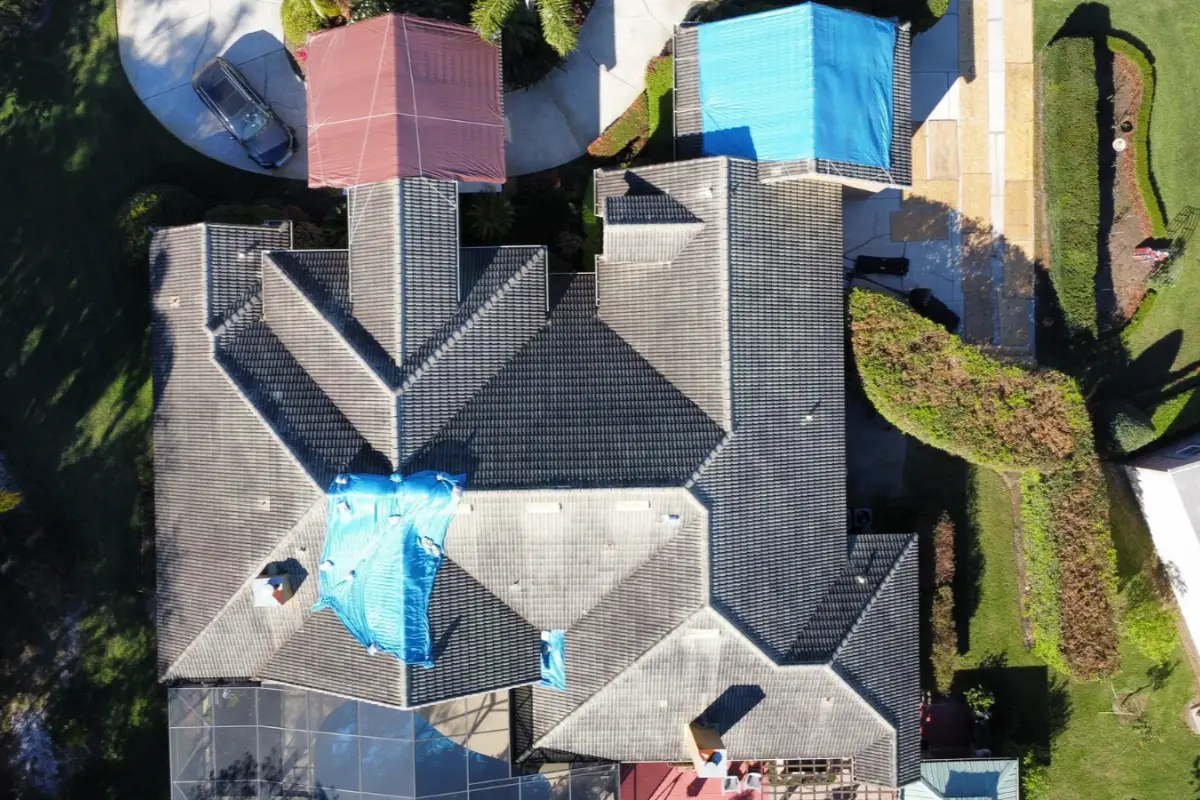 Overhead drone view of roof installation in progress with protective coverings on sections of roof